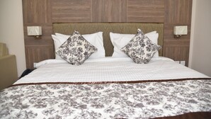 Une chambre d’hôtel avec une tête de lit en bois, deux lampes de chevet, une couvre-lit à motifs floraux et un oreiller assorti.