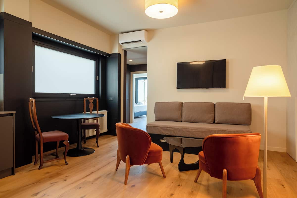 Ein modernes Wohnzimmer mit einer Couch, zwei Sesseln, einem Couchtisch und einem Fernseher.