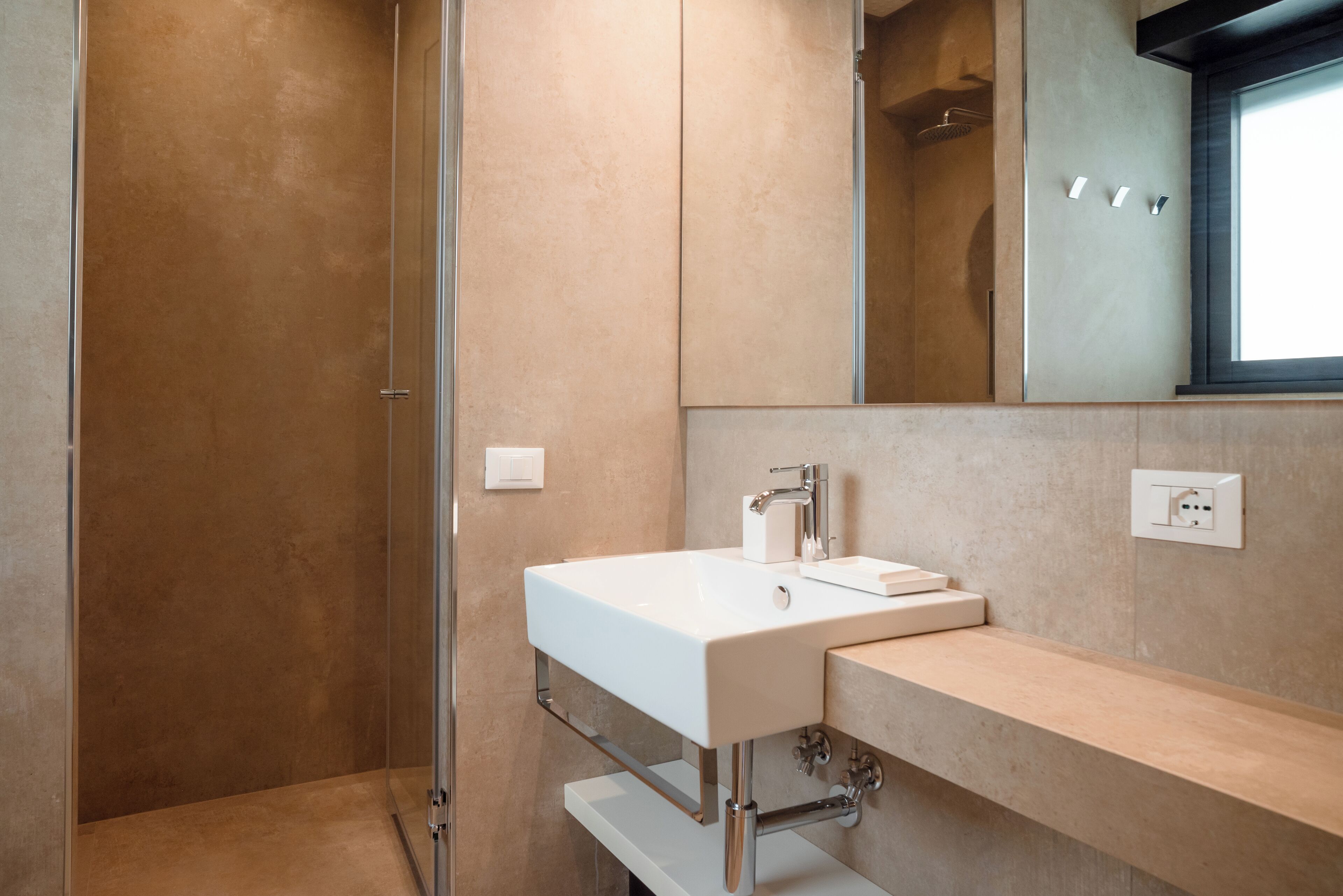 A modern bathroom with a white sink, a mirror, and a shower enclosure.