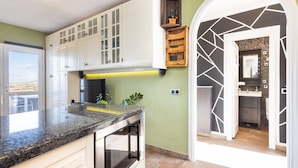 A kitchen with white cabinets, a granite countertop, and a built-in oven.