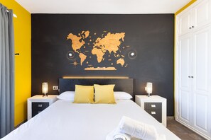 Ein Hotelzimmer mit einem großen Bett, zwei Nachttischen mit Lampen, einer Weltkarte an der Wand und einem Kleiderschrank.