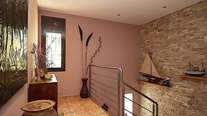 A staircase with a metal railing, a wall with a stone pattern, and a small shelf with a model ship. - Villa for 8 pers. with private pool in Lloret de Mar (Lloret de Mar)