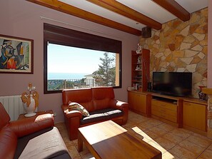 Ein Wohnzimmer mit großem Fenster, Fernseher und Steinwand.