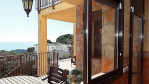 A balcony with a wooden table, chairs, and a potted plant. - Villa for 8 pers. with private pool in Lloret de Mar (Lloret de Mar)