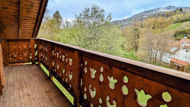 A wooden balcony with a view of a valley and distant buildings. - Spacious chalet in La Bresse, perfect for families and friends (La Bresse)