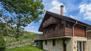 A traditional wooden house with a stone foundation, a balcony with intricate carvings, and a stone wall in the background. - Spacious chalet in La Bresse, perfect for families and friends (La Bresse)