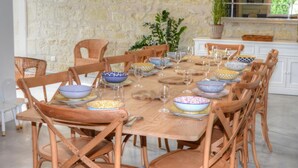 A dining area with a stone wall, wooden chairs, and a variety of patterned bowls and plates. - Charming Touraine cottage with spa and private garden (Saint-Germain-sur-Vienne)