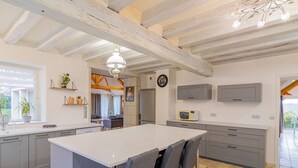 Une cuisine moderne dotée d’un îlot central, de meubles de couleur grise et d’un coin repas avec des chaises grises recouvertes de tissu.
