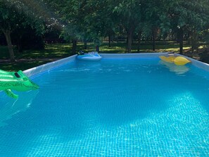 Ein Schwimmbecken mit einem grünen, aufblasbaren Krokodilspielzeug und einem blauen Schwimmreifen.