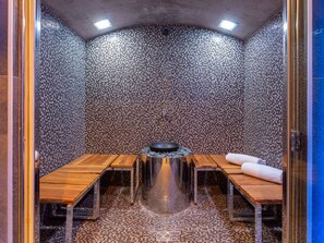 A sauna room with mosaic walls, a central heating element, and wooden benches. - 5★ Chalet with spa, sauna & hammam for 15 people, close to slopes (La Clusaz)