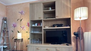 Ein Wohnzimmer mit einer Holz-Unterhaltungsanlage, einem Fernseher und einer Stehlampe.
