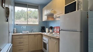 Eine kleine Küche mit Holzausstattung, einem Backofen, einer Mikrowelle und einem Kühlschrank.