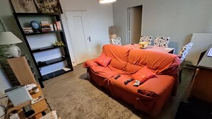 A living room with a red sofa, a bookshelf, and a lamp. - T4 apartment in the center of town (Colomiers)