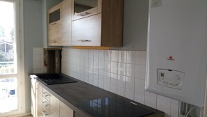 A kitchen with wooden cabinets, a black countertop, and white tiled backsplash. - T4 apartment in the center of town (Colomiers)