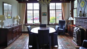 Comedor con una mesa redonda, sillas, chimenea y un ventanal con cortinas.