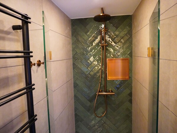 A bathroom with a glass shower enclosure, a towel rack, and a wooden panel. - B&B Catharinenburg (Melissant)