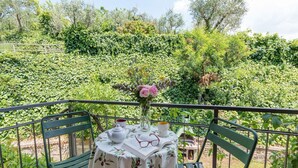 A balcony with a table set for two, a vase with flowers, and a book. - Cosy apartment in villa for 2 guests with A/C, WIFI, pool, TV and patio, close to San Gimignano (Gavignano)