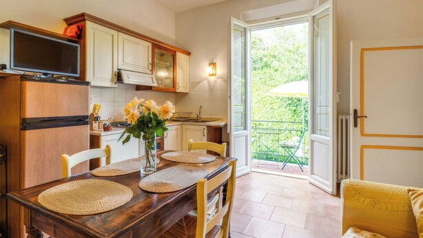 A kitchen with a dining table, chairs, a TV, and a window to the outside. - Cosy apartment in villa for 2 guests with A/C, WIFI, pool, TV and patio, close to San Gimignano (Gavignano)