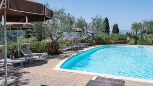 A swimming pool with lounge chairs and umbrellas, surrounded by greenery and trees. - Cosy apartment in villa for 2 guests with A/C, WIFI, pool, TV and patio, close to San Gimignano (Gavignano)
