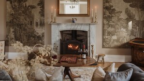 Una sala de estar acogedora con chimenea, una mesa redonda de madera y un sofá cómodo.