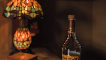 A bottle of Glenmorangie whisky on a wooden table with a stained glass lamp and a metal tray with glasses.