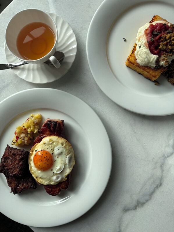 Tres platos de comida para el desayuno, una taza de té y una cuchara sobre una mesa de mármol.
