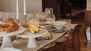 Una mesa de desayuno con pasteles, plátanos y velas.