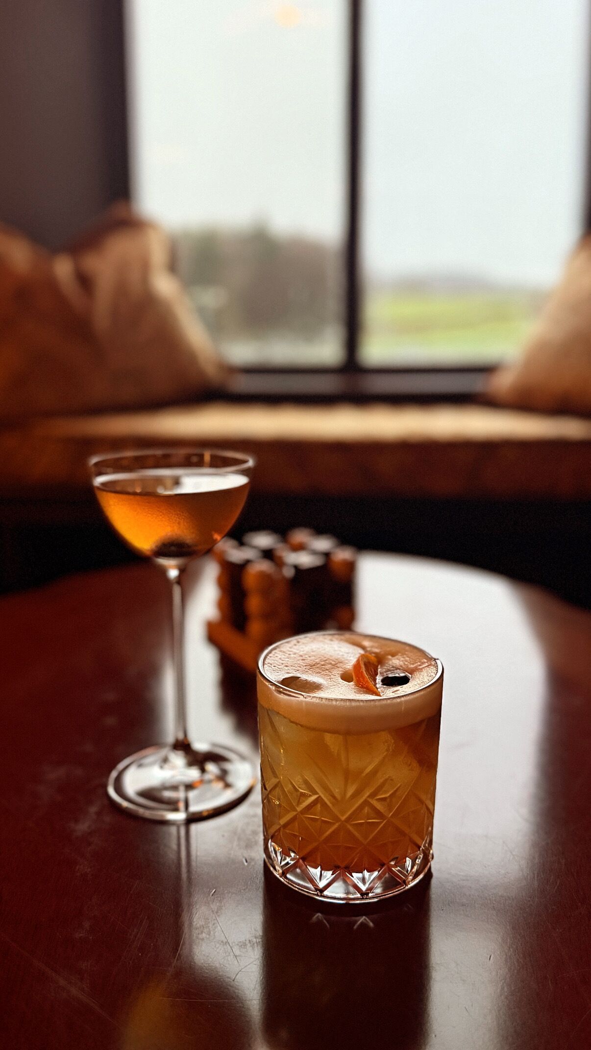 A bar area with a glass of amber-colored beverage and a martini glass.