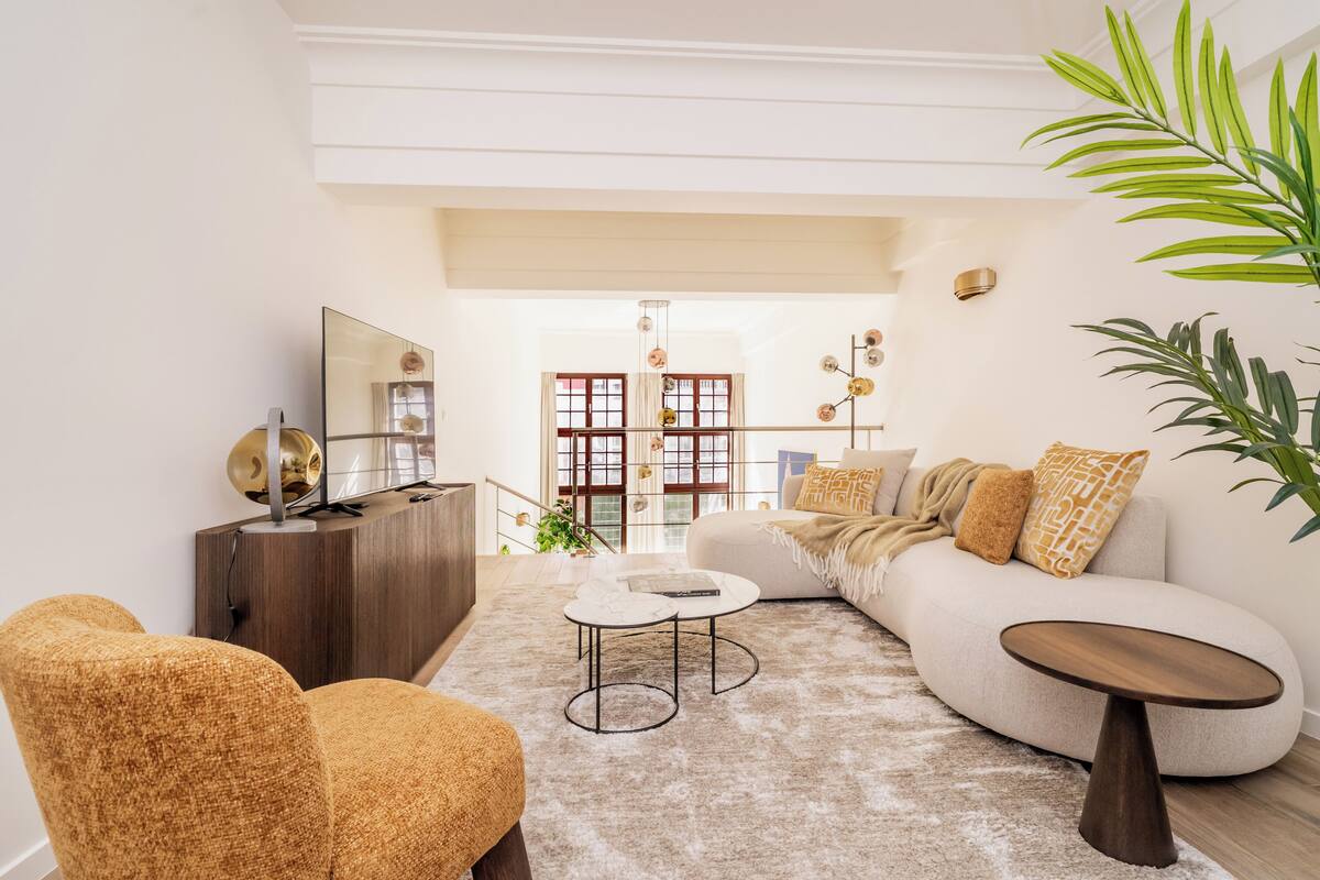 A modern living room with a sofa, armchairs, a coffee table, and a TV on a wooden cabinet.