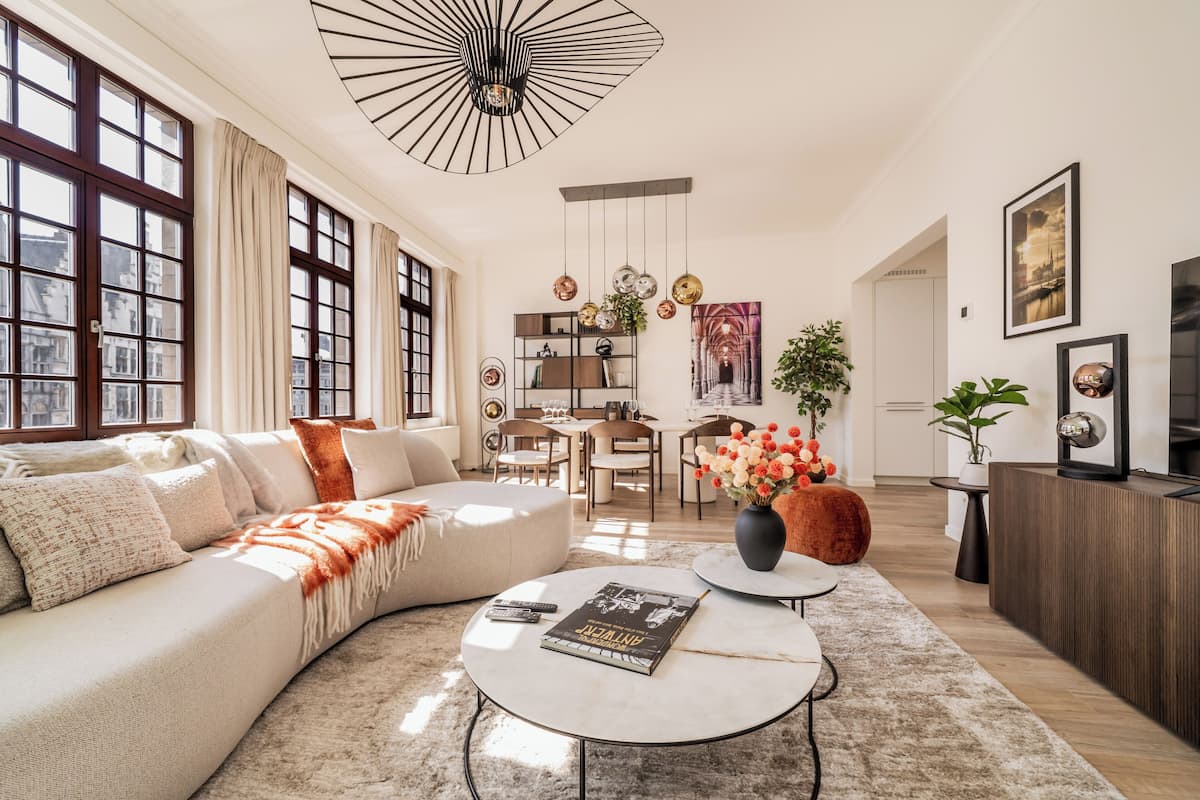 A modern living room with a sofa, coffee table, and a dining area with chairs and a table.