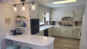 Una cocina moderna con armarios blancos, una isla central con taburetes y una lámpara colgante.