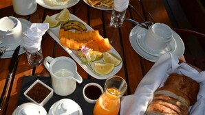 A breakfast setting with plates of food, a pitcher of orange juice, and bread. - Maggie Resthouse (Dar es Salaam)