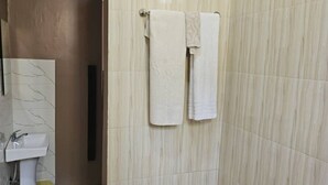 A bathroom with a marble sink, a towel rack with two towels, and a toilet. - Maggie Resthouse (Dar es Salaam)