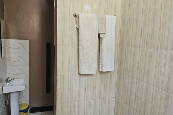 Un baño con un lavabo de mármol, un perchero con dos toallas y un inodoro.