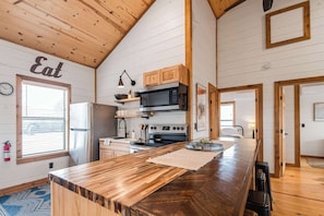 A kitchen with wooden cabinets, a microwave, a stove, and a large wooden countertop.