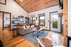 A spacious living room with a wooden ceiling, a sofa, a coffee table, and a rug.