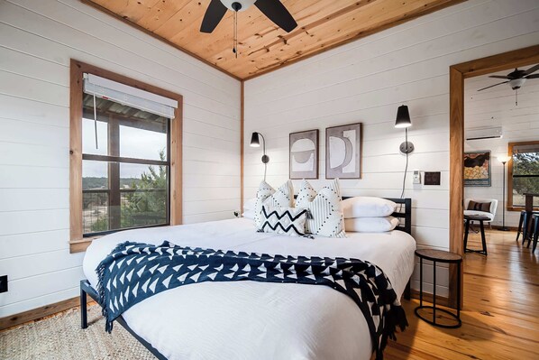 A bedroom with a large bed, wooden ceiling, and a view of the outdoors.