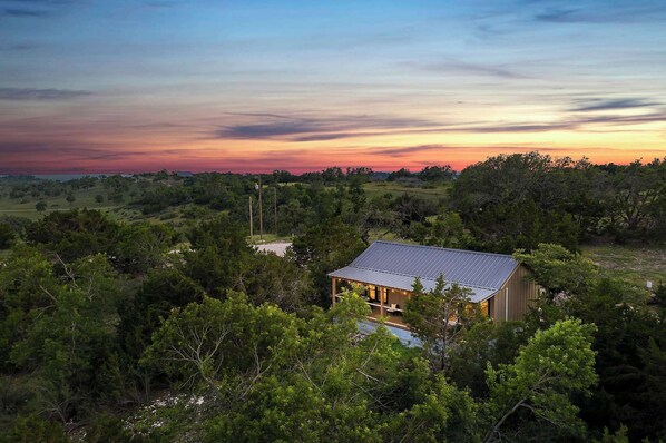 A house surrounded by dense trees with a clear view of the sky.
