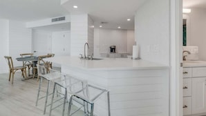 Une cuisine moderne dotée d’un îlot central, de meubles blancs et d’un coin repas avec une table ronde et des chaises.