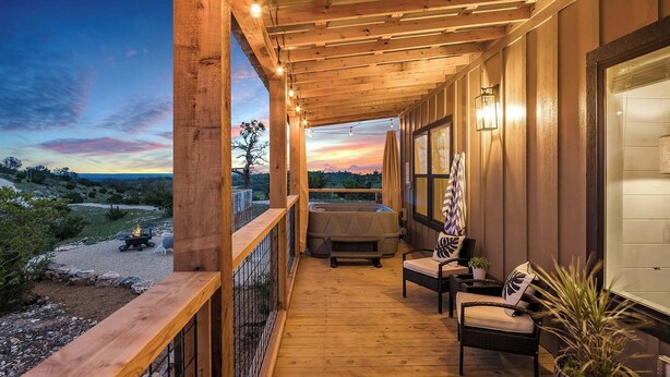 A wooden deck with a hot tub, outdoor seating, and a view of the landscape.