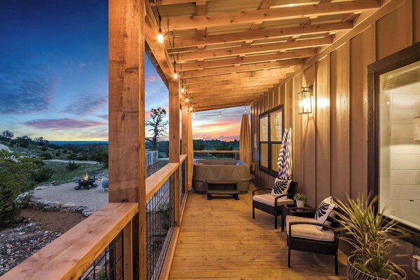 Una terraza de madera con hidromasaje, mobiliario exterior y vistas del paisaje.