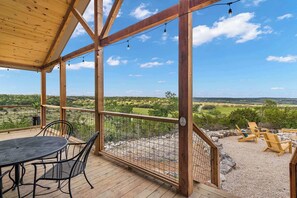 Um deck de madeira com mesa e cadeiras, com vista para uma paisagem deslumbrante.
