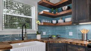 A kitchen with a white sink, wooden countertops, and blue-tiled backsplash. - Modern Ranch Retreat with Hill Country Views (Gillespie County)