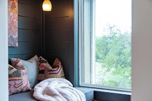 A cozy seating area with a window, pillows, and a blanket.
