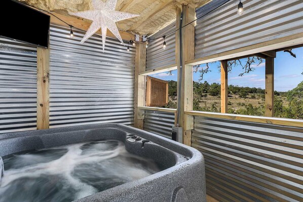 Un jacuzzi en una cabaña rústica con decoración de estrellas, vigas de madera y vistas al paisaje desértico.