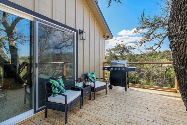 A deck with wicker furniture and a barbecue grill.