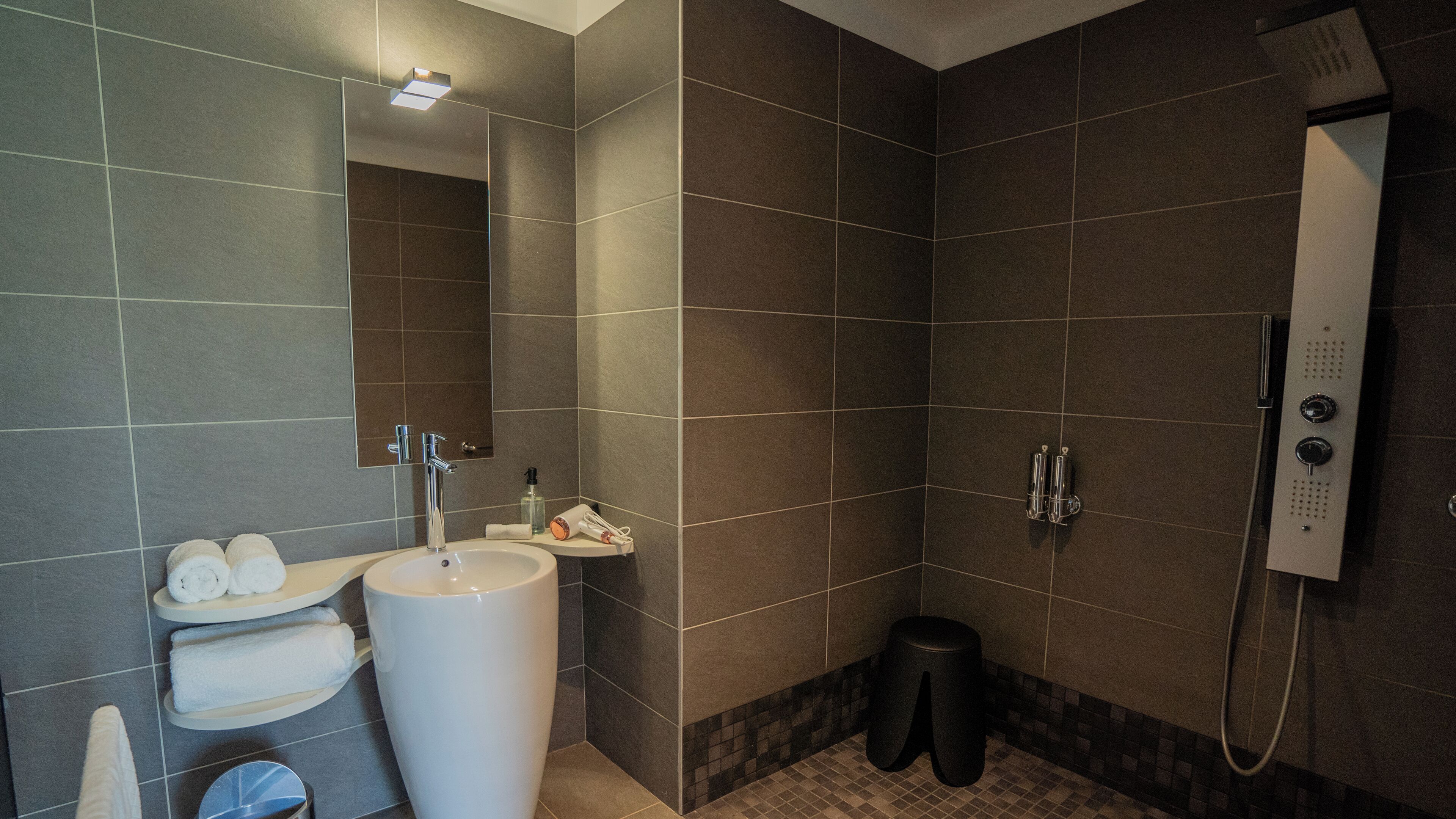 Un baño moderno con un lavabo amplio, espejo y ducha.