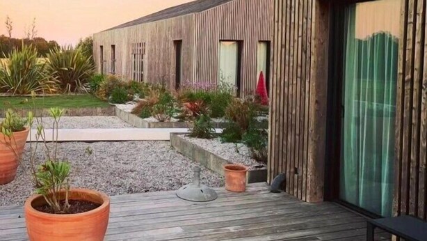 A modern building with a wooden facade and a deck area with potted plants. - Les Villas du Parc de la Chabotterie (Montréverd)