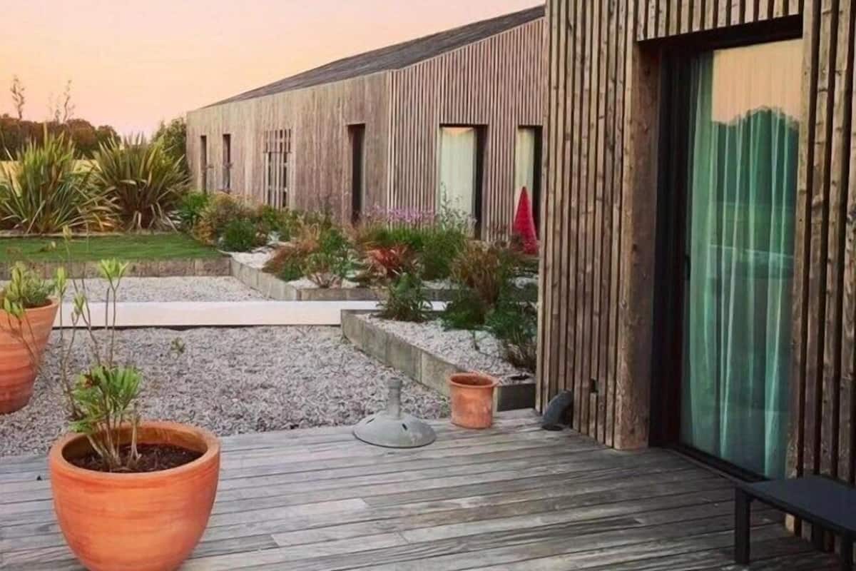 Ein modernes Gebäude mit Holzfassade und einer Terrassenfläche mit Topfpflanzen.
