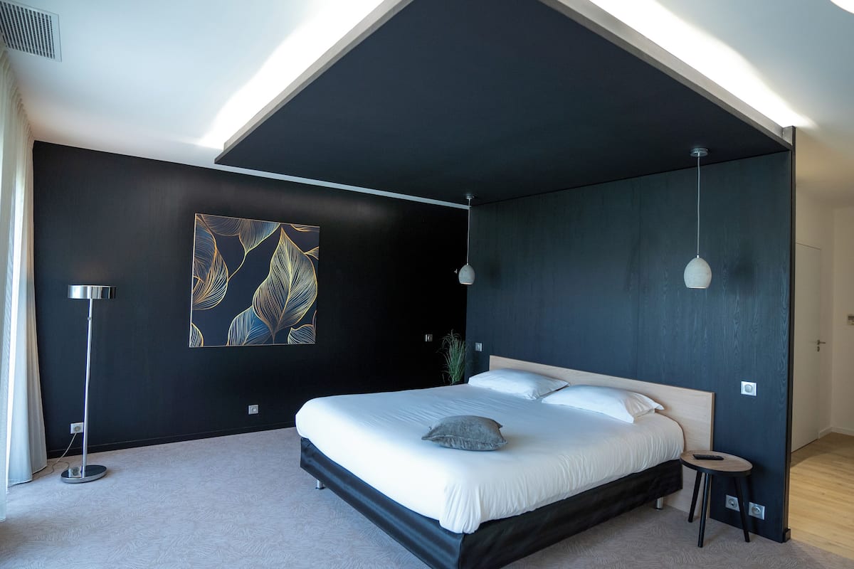 Ein modernes Schlafzimmer mit einem großen Bett, einer Deckenleuchte und einem Wandbild.